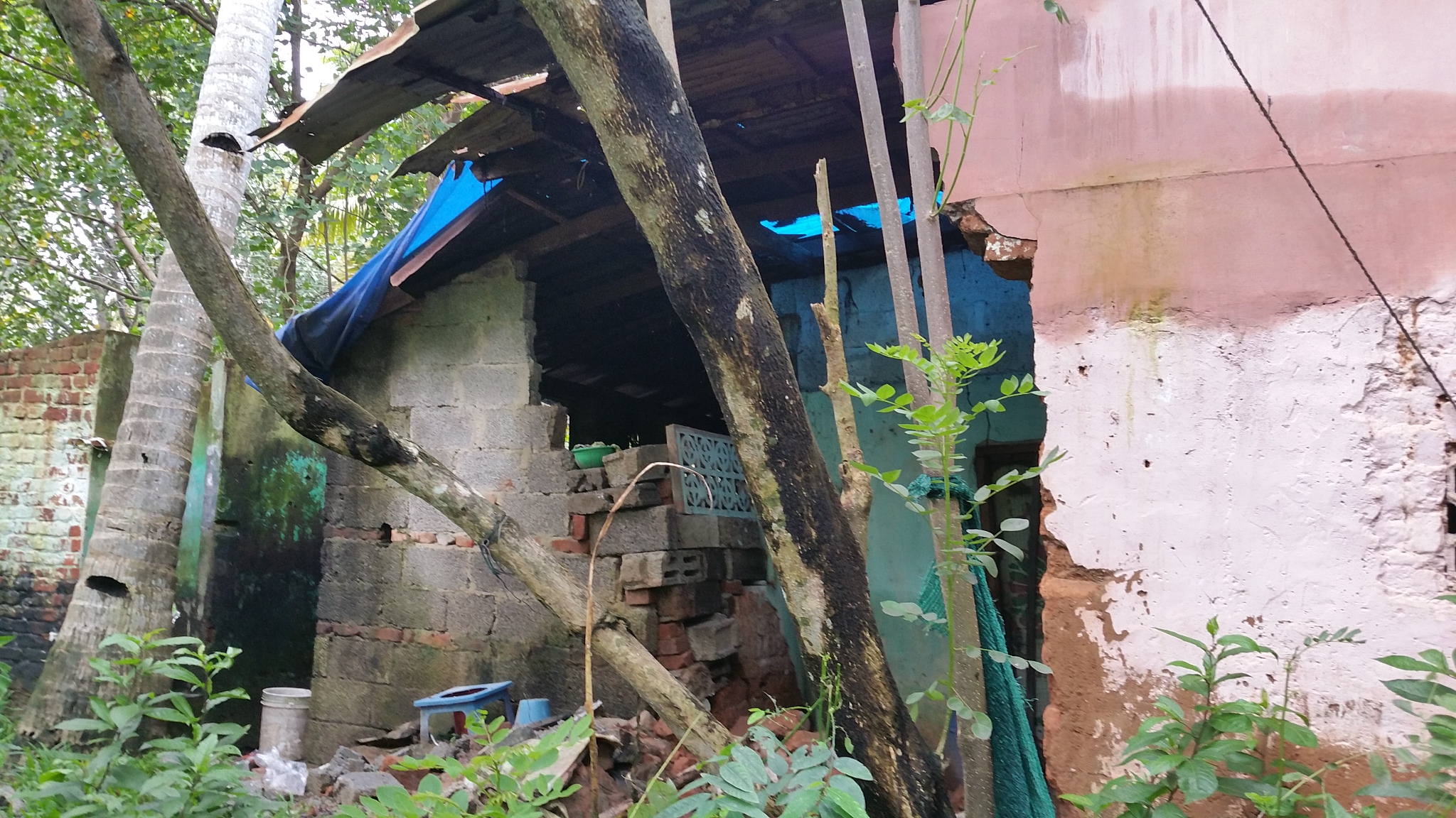 House with fallen wall in a Trivandrum slum after floods